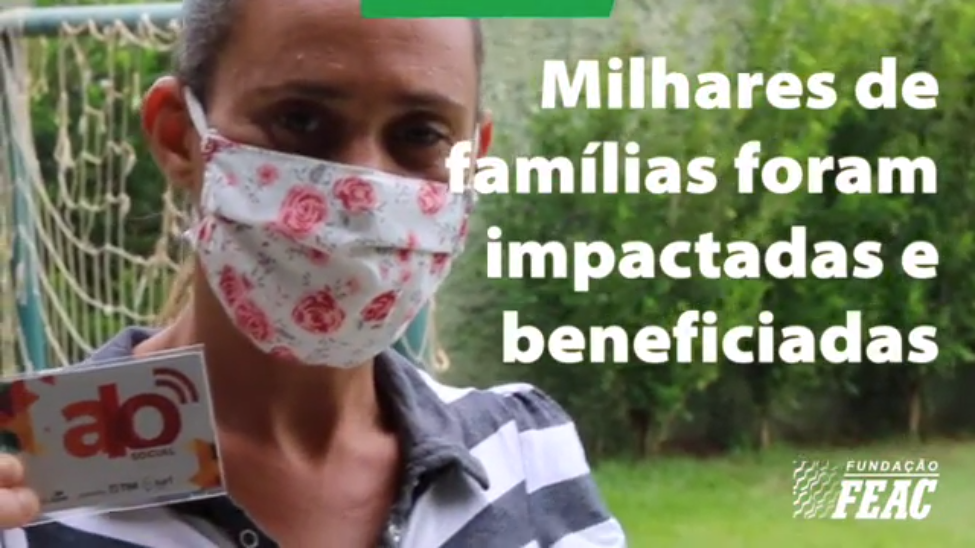 Imagem do vídeo mostra uma mulher, com máscara, segurando um cartão do Família On e o texto: "Milhares de famílias foram impactadas e beneficiadas"