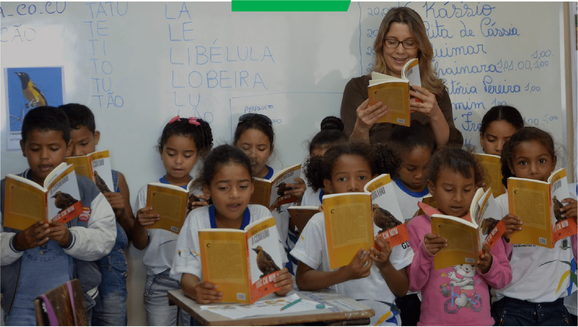 Professora e crianças lendo em conjunto em sala de aula