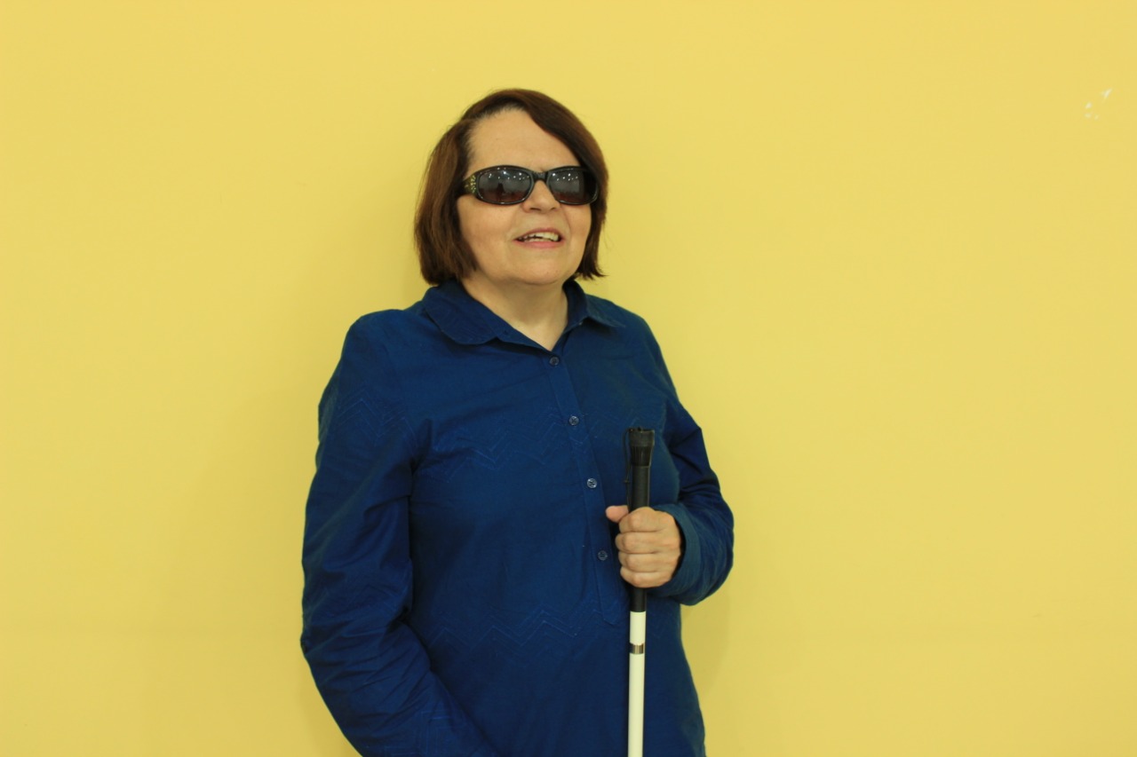 Regina Oliveira, coordenadora de revisão de Braille da Fundação Dorina Nowill. No fundo uma parede amarela