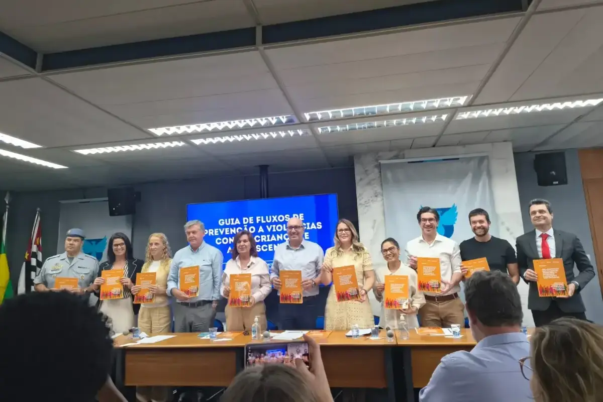 Mesa com autoridades apresentando o Guia de Fluxos de Prevenção à Violência contra Crianças e Adolescentes em evento oficial.