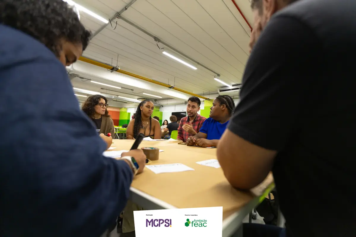 Grupo de pessoas sentadas ao redor de uma mesa durante reunião de trabalho do projeto LabPOP.